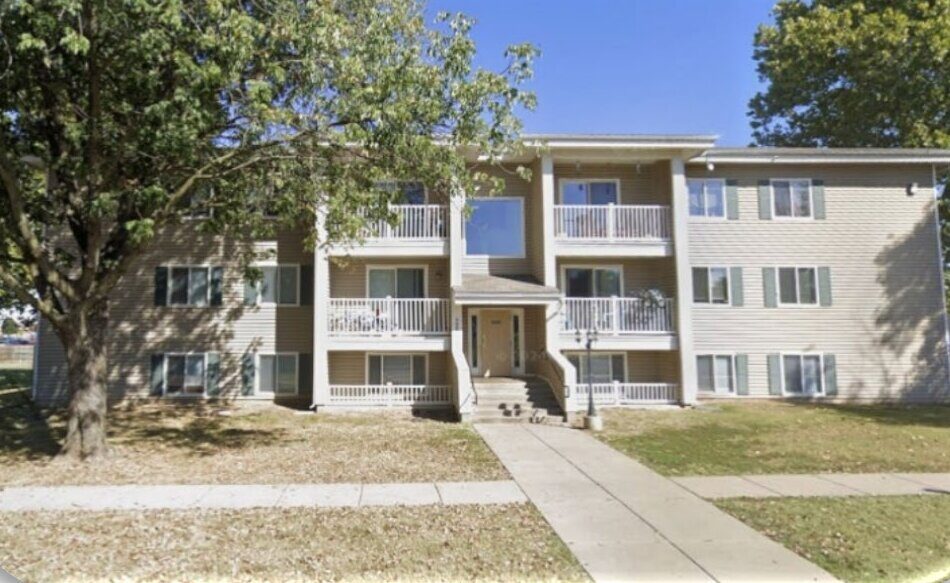 Sycamore Village, Pittsburg, KS — before: a tan-sided garden apartment building